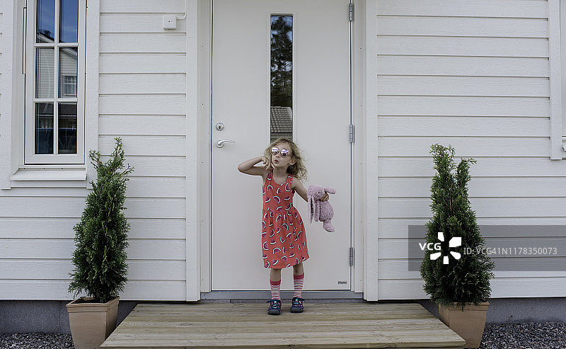 小女孩抱着玩具和宠物狗在户外合影图片素材