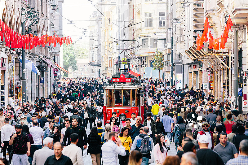 土耳其伊斯坦布尔独立大街上的红色老式有轨电车和人群图片素材