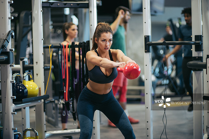 年轻女人在健身房壶铃锻炼图片素材