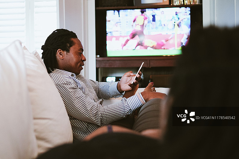 父亲在发短信，母亲在看电视上的体育节目图片素材