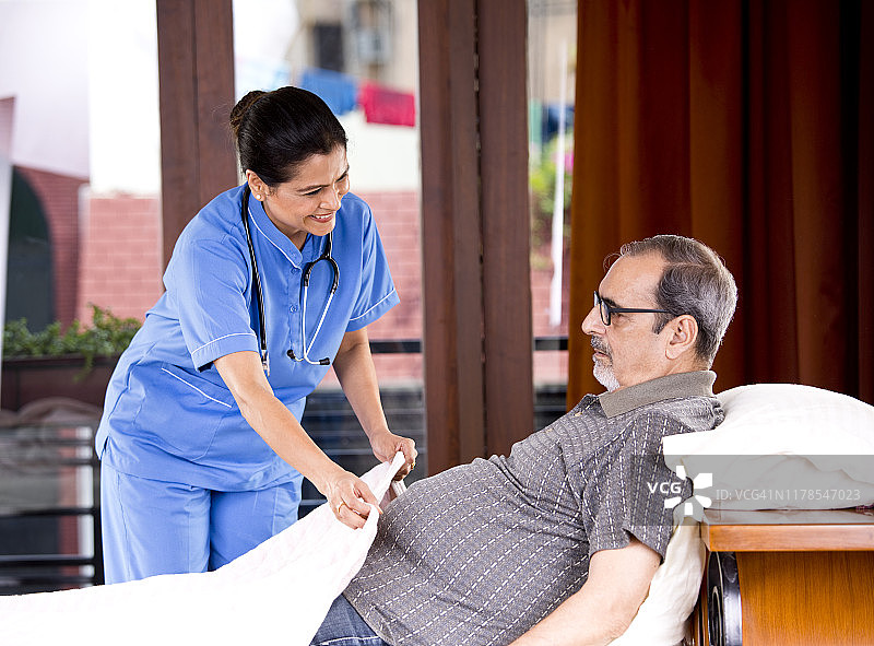 女护士居家护理，帮助老年男子在床上放松图片素材