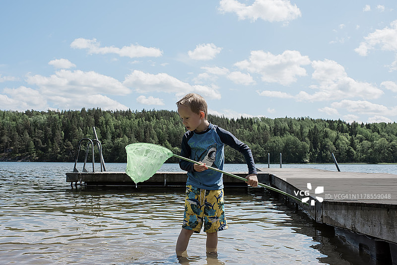 在海滩用网捕鱼的男孩图片素材