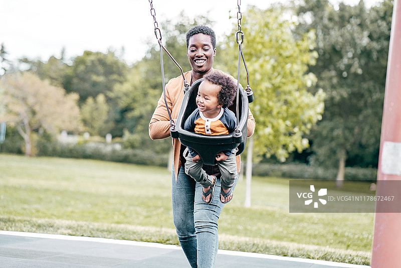 妈妈和蹒跚学步的孩子在操场上图片素材