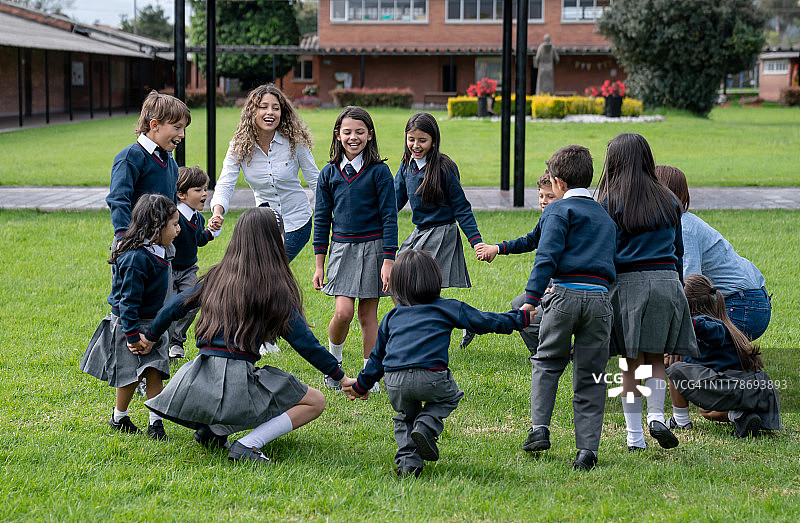 快乐的老师和一群学生在户外玩耍图片素材