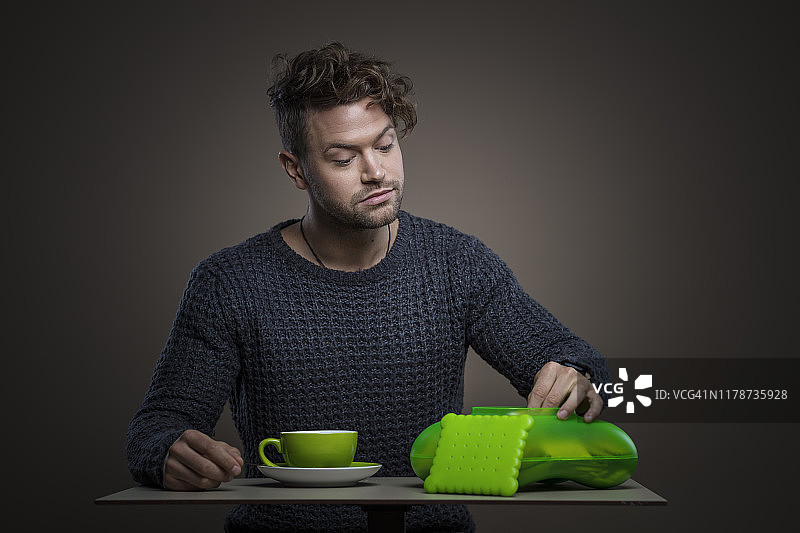 年轻聪明的男人喝咖啡吃饼干图片素材