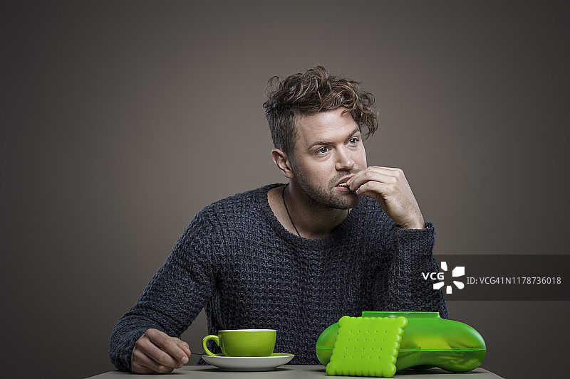 年轻聪明的男人喝咖啡吃饼干图片素材