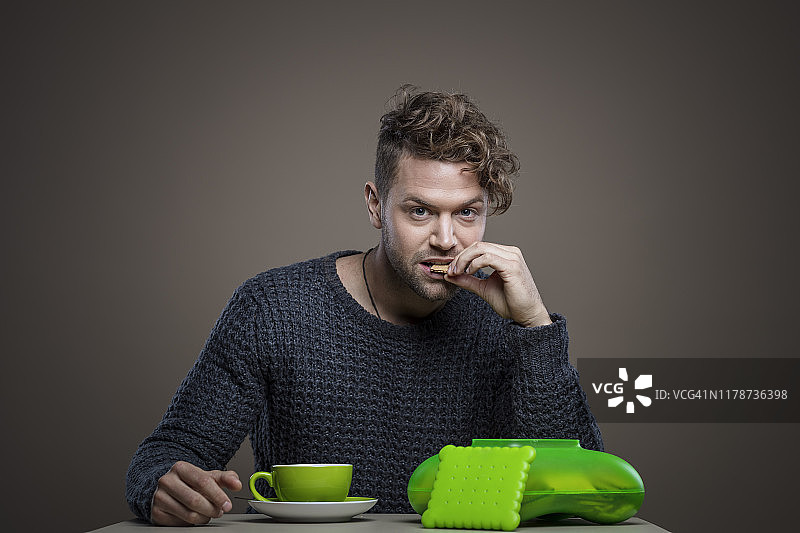 年轻聪明的男人喝咖啡吃饼干图片素材