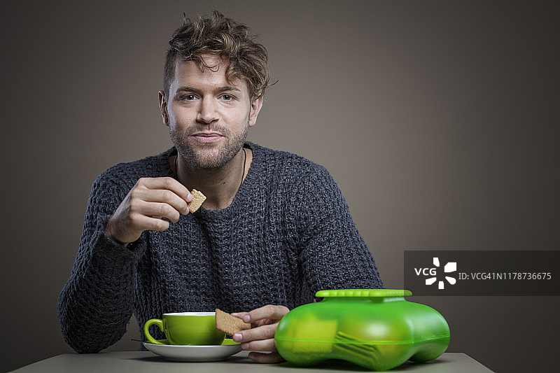 年轻聪明的男人喝咖啡吃饼干图片素材