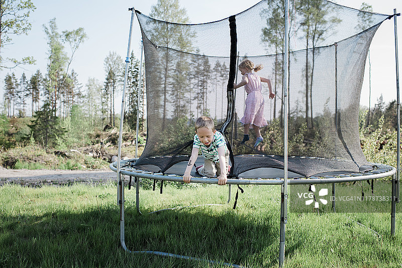 孩子们在家里的花园里玩蹦床图片素材