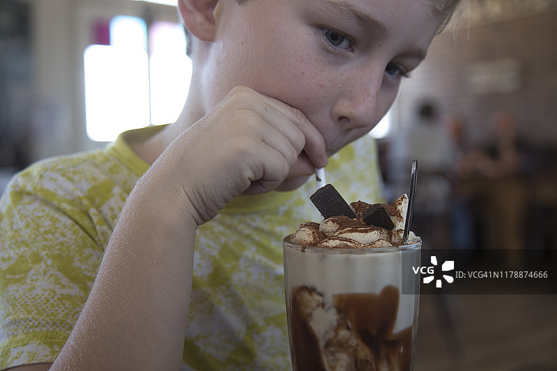 8岁男孩在咖啡馆享用冰巧克力饮品图片素材
