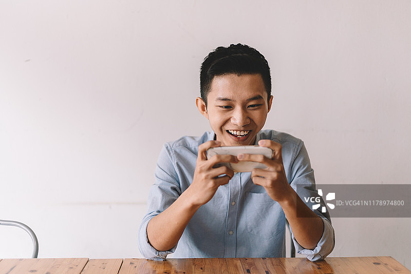 午休期间，一位中国亚洲男人在咖啡馆玩网络游戏获胜图片素材