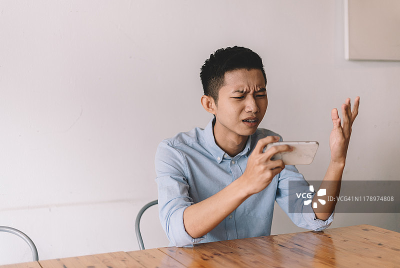 一位中国男性在午休时间于咖啡馆玩在线游戏图片素材
