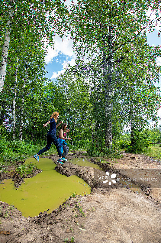 两位女性在俄罗斯乌拉尔山脉跳过水坑图片素材
