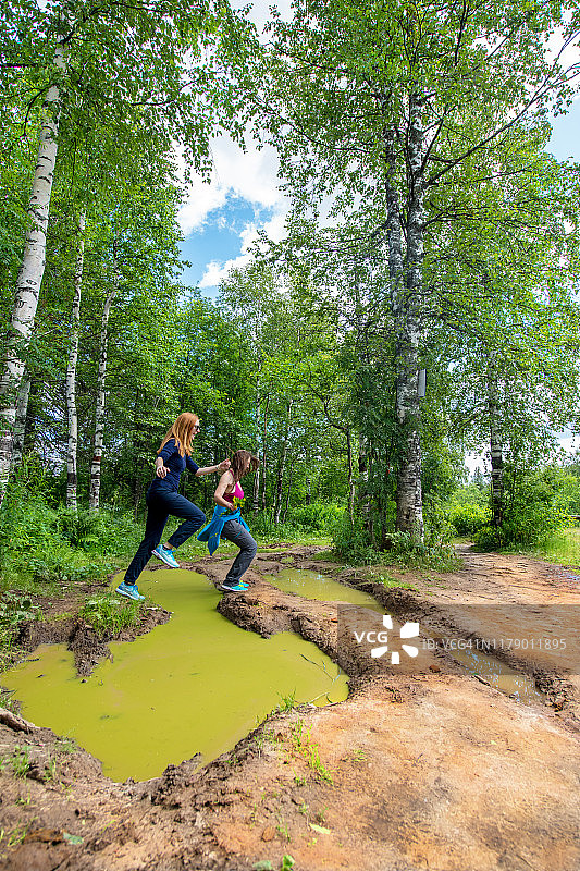 两位女性在俄罗斯乌拉尔山脉跳过水坑图片素材
