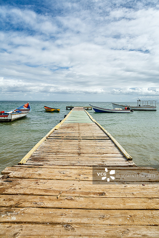 阳光明媚的日子里停泊在木制码头尽头的船只图片素材