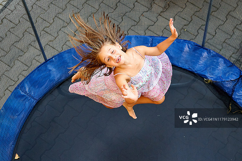 快乐女孩在罗马尼亚特兰西瓦尼亚的户外蹦床上跳跃图片素材