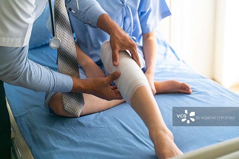 医生用弹性绷带为儿童患者的腿部扭伤进行急救图片素材