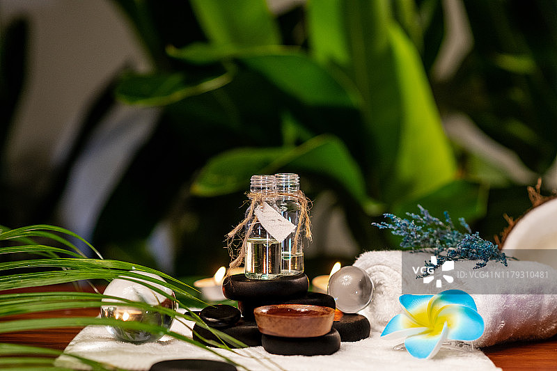 用于芳香疗法的精油罐，置于石头和毛巾上，旁边有毛巾花和薰衣草图片素材
