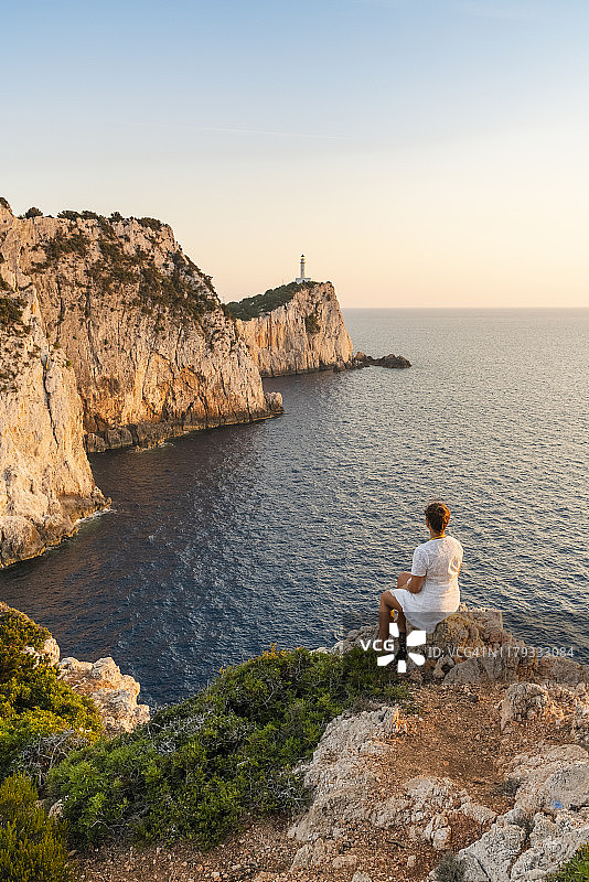 女人观赏希腊莱夫卡达斯莱夫卡塔斯角灯塔后的日落图片素材