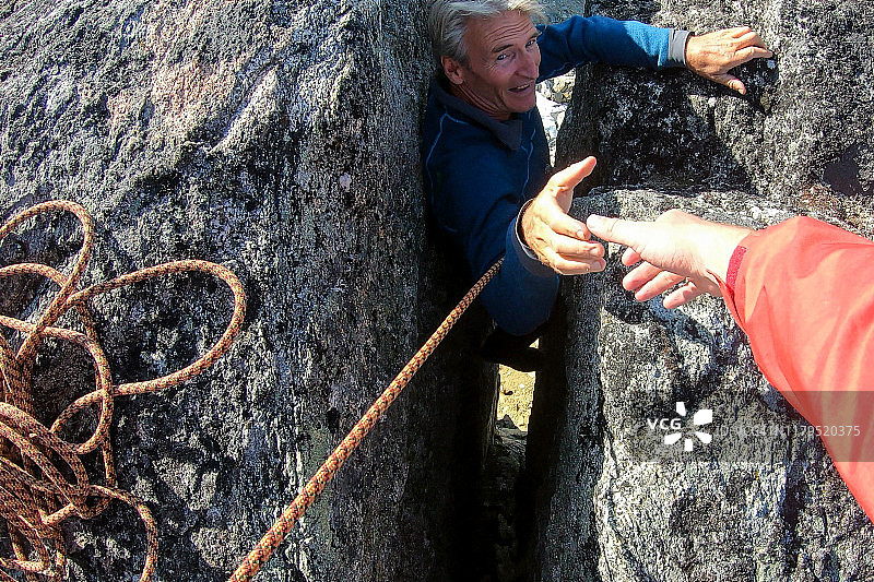 登山者帮助同伴攀登图片素材
