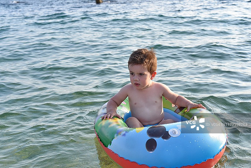 小男孩在充气筏上漂浮在海中图片素材