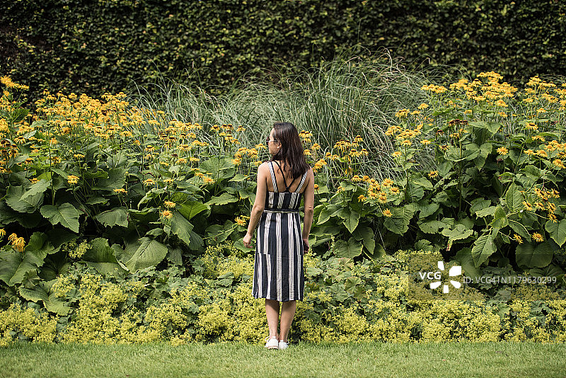 在苏格兰爱丁堡花园里赏花的条纹夏装女人图片素材