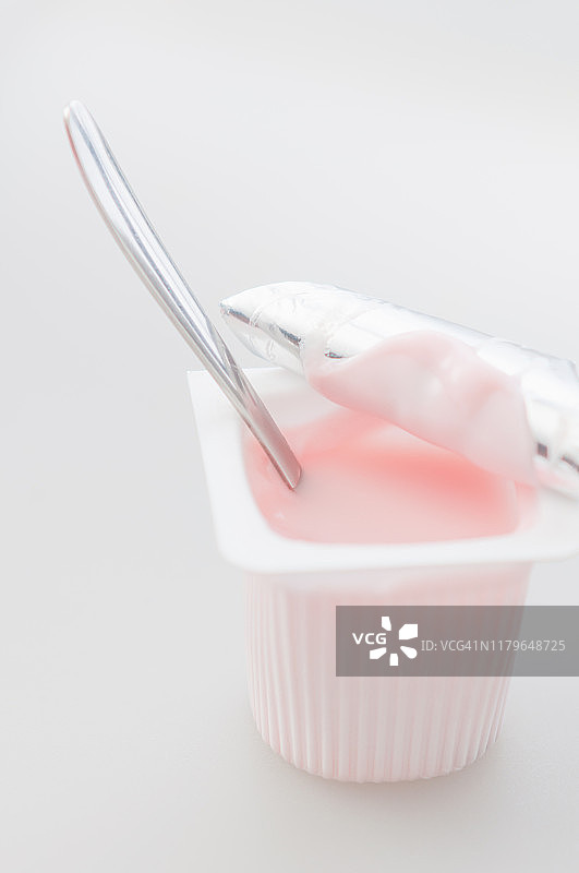 塑料桌上的草莓酸奶杯和茶匙图片素材