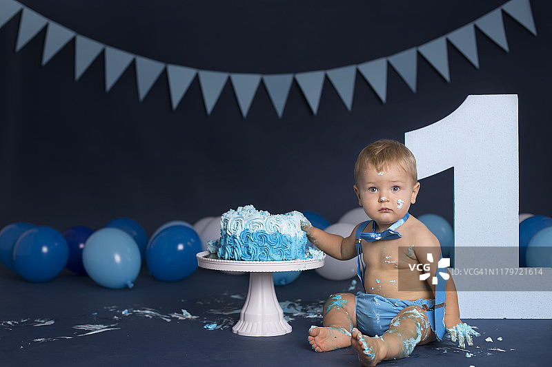 男婴在生日派对上玩蛋糕图片素材