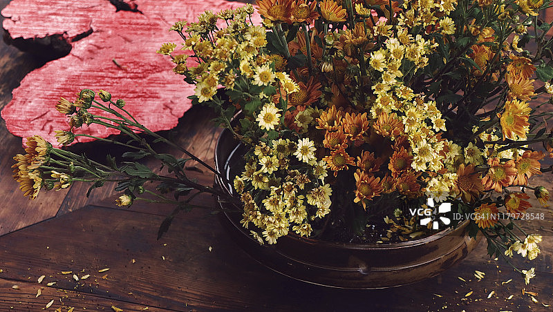 秋日花道：陶瓷扁瓶中黄、橙菊花与飘落花瓣图片素材