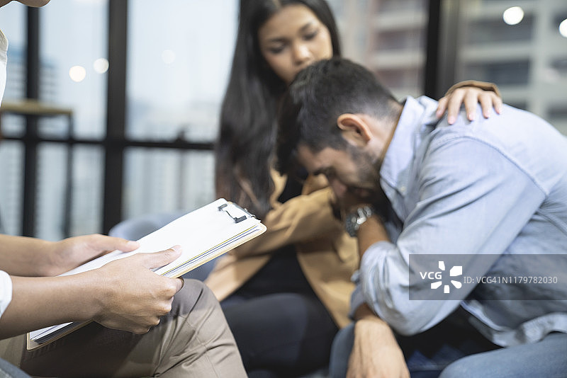心理咨询：女子在心理治疗中拥抱男子的手。图片素材