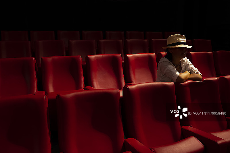 戴帽子的女人独自坐在电影院里图片素材