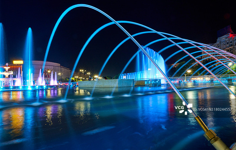夜晚，罗马尼亚布加勒斯特团结大道上的彩色喷泉和议会宫图片素材