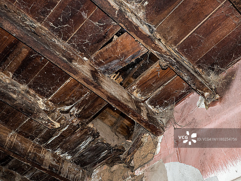 废弃房屋中破损的彩绘木屋顶，有蜘蛛网和灰尘，乡村人口减少概念图片素材