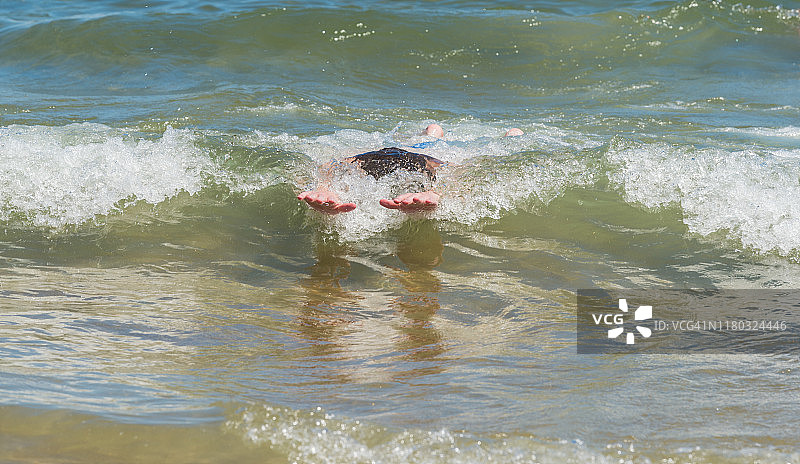 年轻人在海中趴板冲浪图片素材