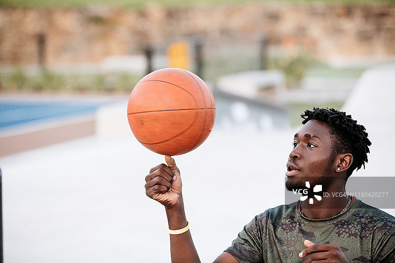 酷炫运动员用拇指旋转篮球的侧面照图片素材