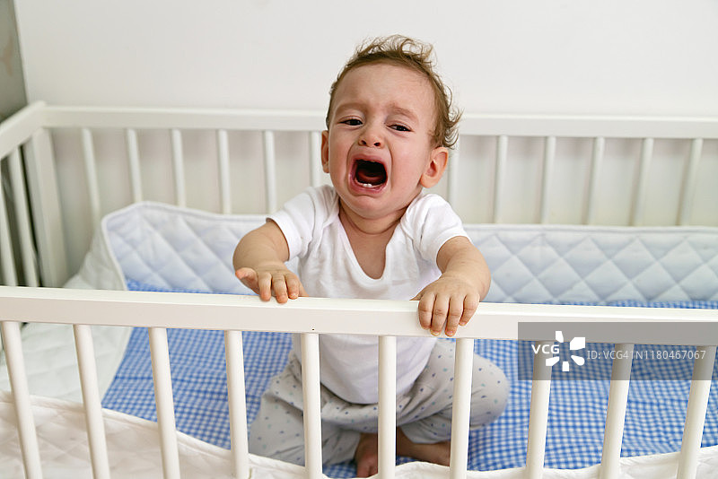 在婴儿床里哭泣的男婴图片素材