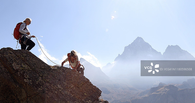 母亲用绳索保护女儿攀登岩脊图片素材