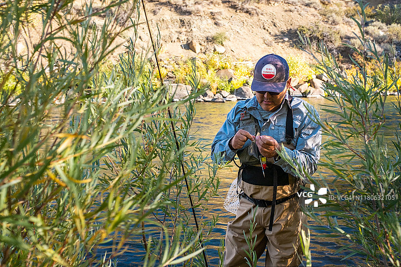 使用欧洲若虫钓法的渔夫在绑鱼钩图片素材