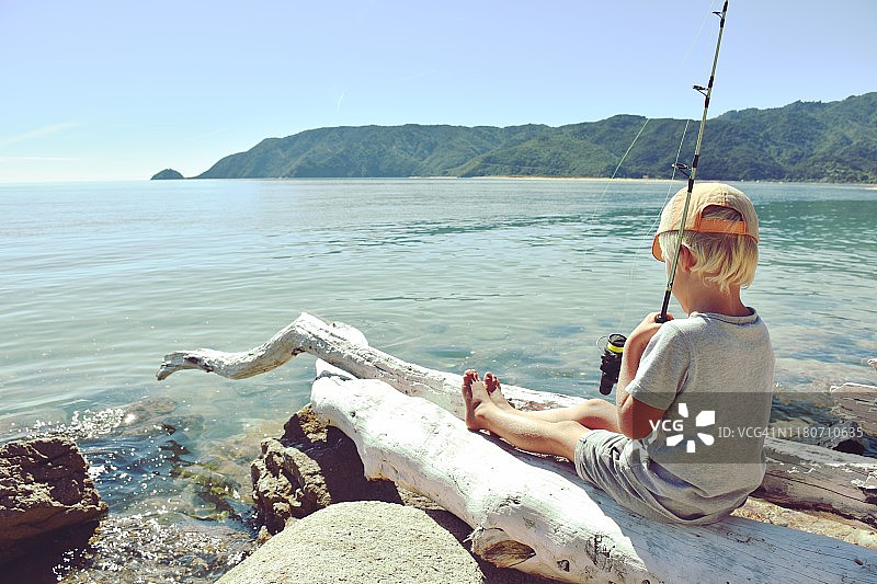 在海岸边钓鱼的年轻男孩图片素材