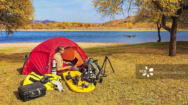 自然摄影师在帐篷内检查设备并操控无人机图片素材
