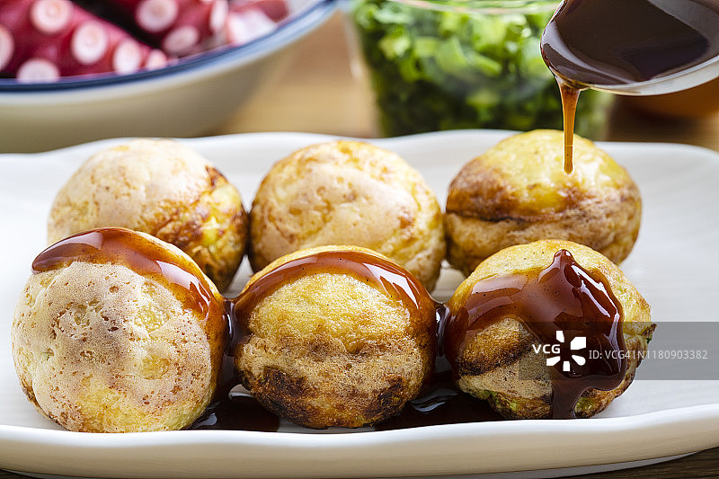 章鱼烧烤食谱。我在章鱼烧上放酱汁。周围。有章鱼、面粉、鸡蛋、卷心菜和大葱。图片素材