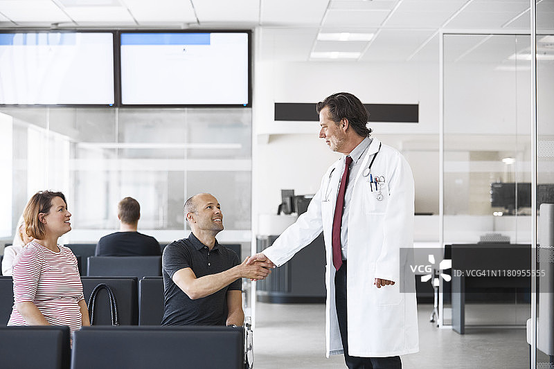 医生与男子握手，孕妇在旁图片素材