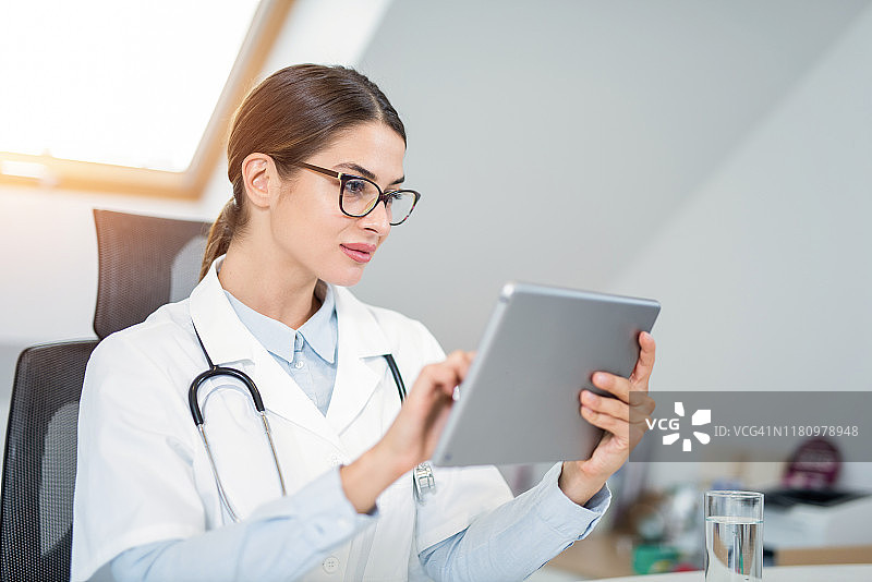 年轻女医生在办公室使用平板电脑图片素材