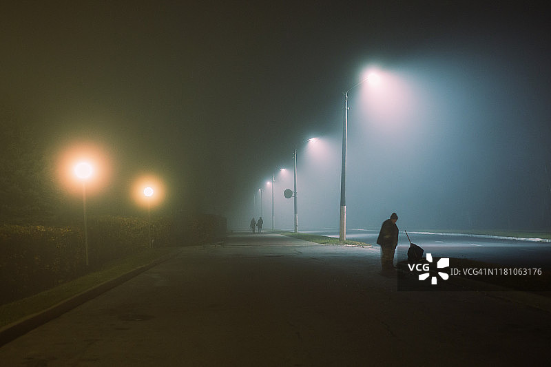 雾中夜景城市背景。黑暗恐怖的夜晚城市中的浓雾。密集的雾中黑暗令人毛骨悚然的神秘城市。幽灵般的雾背景。城市中的黑暗。神奇的雾蒙蒙的景观。神秘的街道图片素材