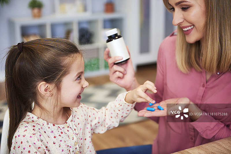 年轻妈妈给小女儿喂药图片素材