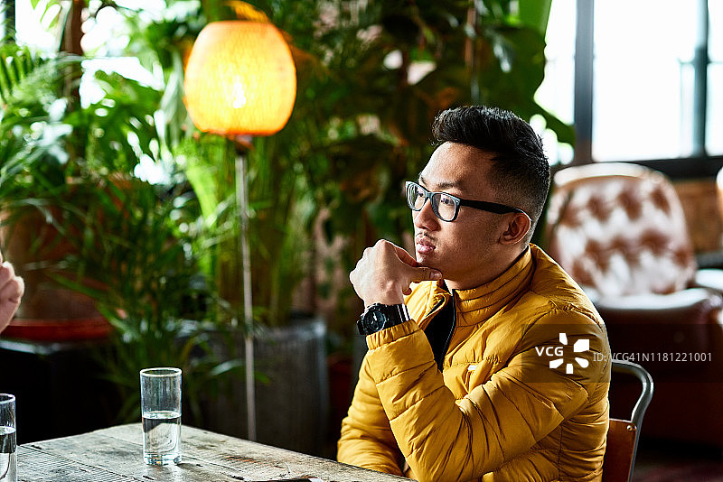 在咖啡馆里听朋友说话的越南男子图片素材