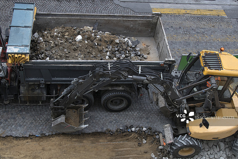 挖掘机将垃圾放入自卸卡车，道路施工现场图片素材