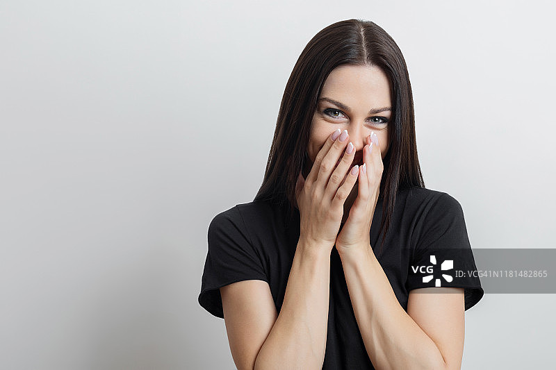 快乐的年轻女人用双手捂住脸图片素材