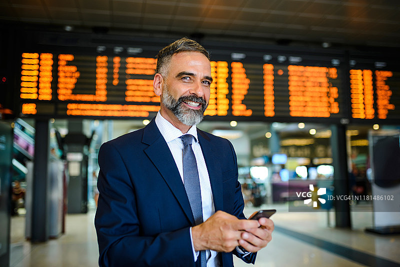 在机场查看航班的微笑的商人图片素材