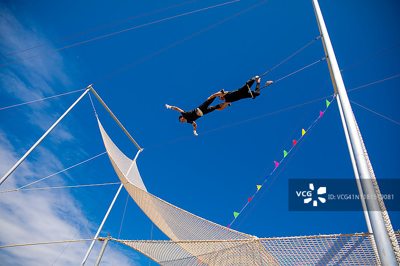 在蓝天下一起荡秋千的杂技演员图片素材